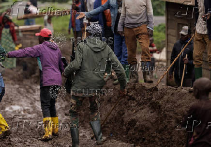 An M23 rebel walks on a muddy road on the outskirts of Rubaya