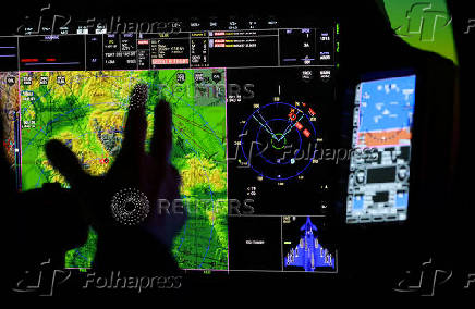 A member of BAE Systems staff demonstrates a new and improved cockpit display for the companies Typhoon military jets in an aircraft simulator at their Warton factory in Warton