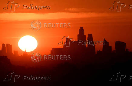FILE PHOTO: The sun rises behind the skyline of St Paul's Cathedral and the City of London, in London