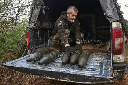 A Ukrainian serviceman unload shells for a howitzer before firing towards Russian troops at a front line in Zaporizhzhia region