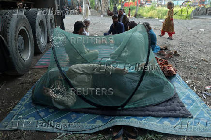 An Afghan man rests in a mosquito net tent beside a loaded truck as he prepares to return home, after Pakistan started to deport documented Afghan refugees, in Nowshera