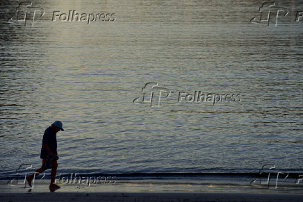 Pedestre caminhando em praia ao amanhecer