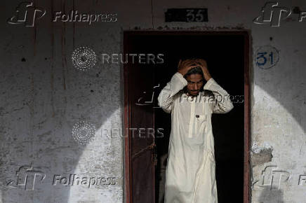 Teen adjusts prayer cap before starting studies at madrasa in Multan