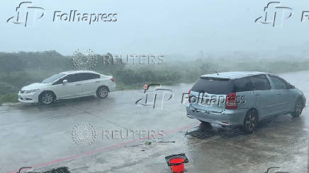 Vehicles stand on a road during a storm, in Green Island