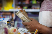 FILE PHOTO: A man holds Indian currency notes inside a shop in New Delhi