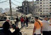 People stand together at a damaged site in the aftermath of Israeli strikes, at Beirut's southern suburbs