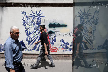 FILE PHOTO: People walk past an anti-U.S. mural on a street in Tehran