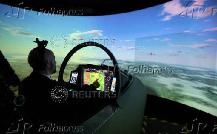 A member of BAE Systems staff demonstrates a new and improved cockpit display for the companies Typhoon military jets in an aircraft simulator at their Warton factory in Warton
