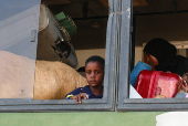 Displaced people leave a camp following a drone strike in Ad-Damar
