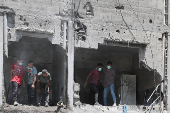 Palestinians inspect the damage at the site of an Israeli strike on a house, in Gaza City