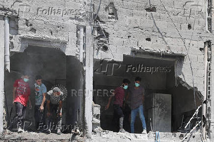 Palestinians inspect the damage at the site of an Israeli strike on a house, in Gaza City