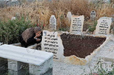 Palestinians visit graves of their relatives at a cemetery in Jenin camp