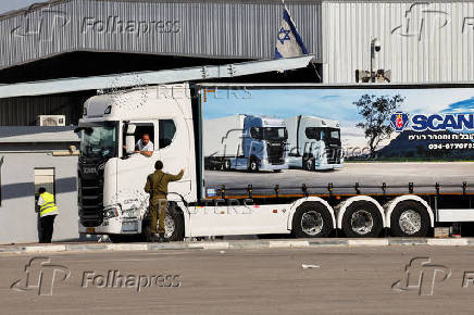 An Israeli security forces member speaks to the driver of a truck carrying aid at the Kerem Shalom crossing between Israel and Gaza, before going into Gaza, on the Israeli side of the Israel-Gaza border
