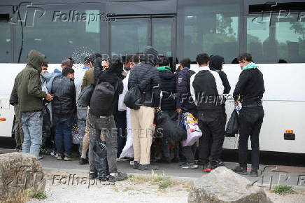 A group of migrants wait to board a coach organised by the authorities in Gravelines
