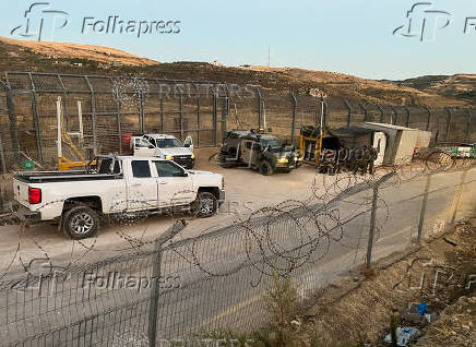 Israeli soldiers stand guard next to a gate on the Golan Heights side