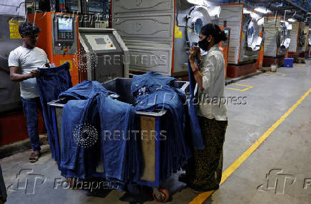 Employees check colour of washed jeans pants in a washing area of a garment manufacturing unit on the outskirts of Ahmedabad