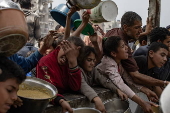 Displaced Palestinians collect donated food in Jabalia, northern Gaza