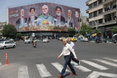 Iranians walk next to a billboard in Tehran
