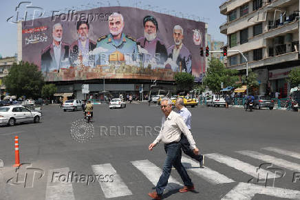 Iranians walk next to a billboard in Tehran