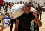Palestinians carry aid supplies they received from the U.S.-backed Gaza Humanitarian Foundation, in Khan Younis