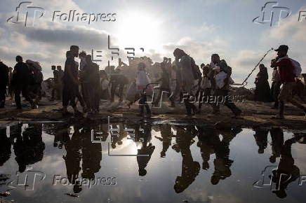 Displaced Palestinians carry relief parcels along Rashid Street, west of Gaza City