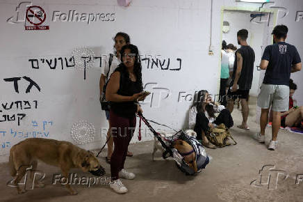 People take shelter during a siren as missiles are launched from Iran towards Israel