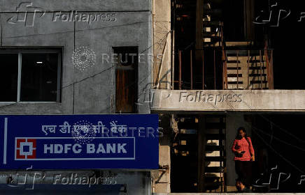 FILE PHOTO: A woman walks past a signboard of HDFC Bank's automated teller machine (ATM) in New Delhi