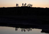 People walk during sunset in Makronissos beach in the resort of Ayia Napa