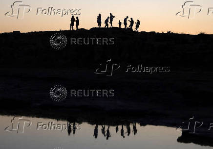 People walk during sunset in Makronissos beach in the resort of Ayia Napa