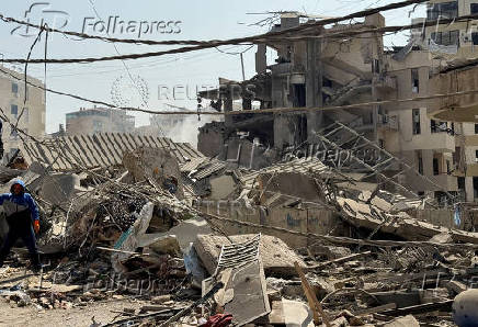 A man stands next to rubble at a damaged site in the aftermath of Israeli strikes, in Beirut's southern suburbs