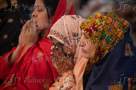 Woman raises henna adorned hands in devotion after Eid ul-Adha prayer in Lahore