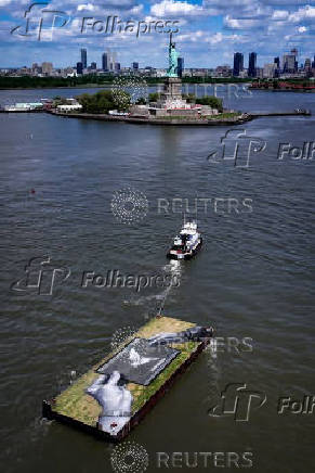 Drone view shows a grass covered barge with painting by Franco-Swiss artist Saype entitled ?Address Hate? towed past Statue of Liberty in New York Harbor