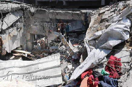 Palestinians inspect the damage at the site of an Israeli strike on a house, in Gaza City