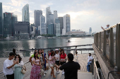 People take photos of the central business district skyline in Singapore