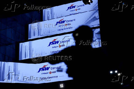 A cameraperson records a video during the listing ceremony of JSW Cement at the National Stock Exchange (NSE) in Mumbai