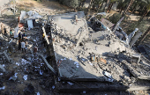 Palestinians inspect the damage at the site of an Israeli strike on a house, in Deir Al-Balah in the central Gaza Strip