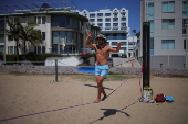 A man walks along a slack rope at Muscle Beach in Santa Monica