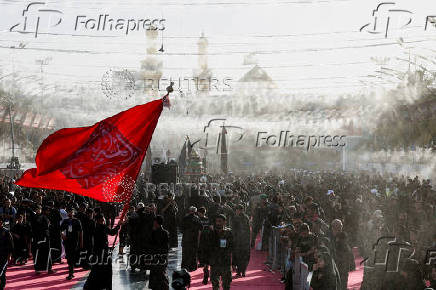 Shi'ite Muslims cool off under water sprinklers amid high temperatures in Karbala
