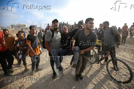 Palestinians carry a wounded man, in Beit Lahia