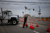 A police officer makes way for a truck to enter Pacific Coast Highway as it reopens, in Los Angeles