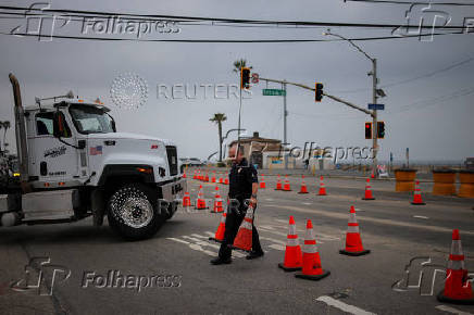A police officer makes way for a truck to enter Pacific Coast Highway as it reopens, in Los Angeles