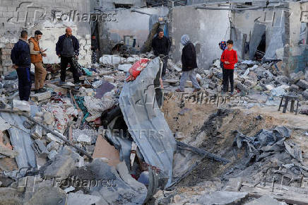Palestinians inspect the site of an Israeli strike on a house, in Khan Younis