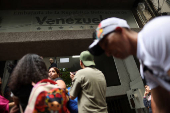 Migrants gather outside the Venezuelan embasssy waiting for a flight back to their country