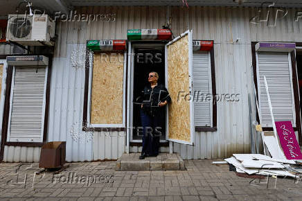 A shop owner shows the damage to her store following the shelling of a market in Donetsk