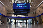 People pass by a screen showing KOSPI at the Korea Exchange in Seoul