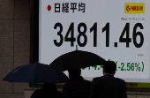 Pedestrians walk past a stock quotation board showing Nikkei share average outside a brokerage in Tokyo
