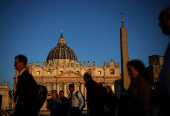 People walk in front of St. Peter's Basilica in St. Peter's Square ahead of the conclave, which will be held on May 7, at the Vatican