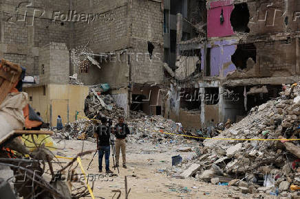 Members of the media report from the ground near a five-storey residential building that collapsed on Friday, July 4, in Karachi