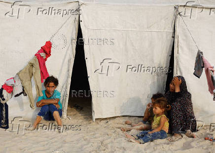 Palestinians, displaced by the Israeli offensive, rest outside their tent where they shelter on a beach amid summer heat, in Gaza City