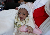 A health worker holds a Palestinian child who was brought to Jordan through King Hussein Bridge crossing to receive medical treatment, in Amman